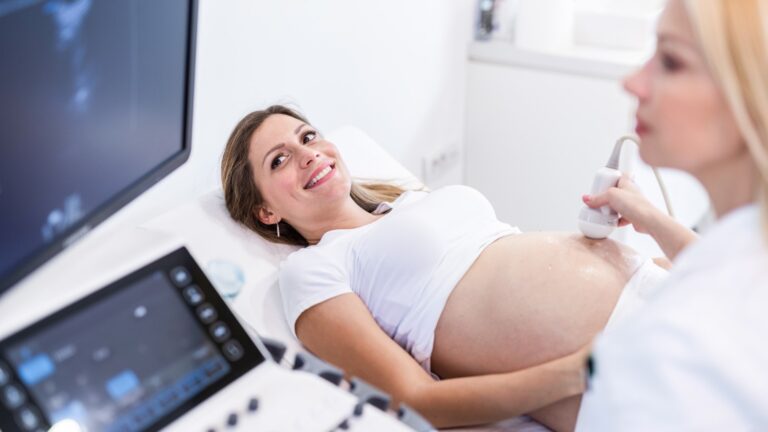 Schwangere Frau erhält eine Bauchultraschalluntersuchung durch eine medizinische Fachkraft in einer Klinik, symbolisiert Schwangerschaftsvorsorge und pränatale Betreuung.